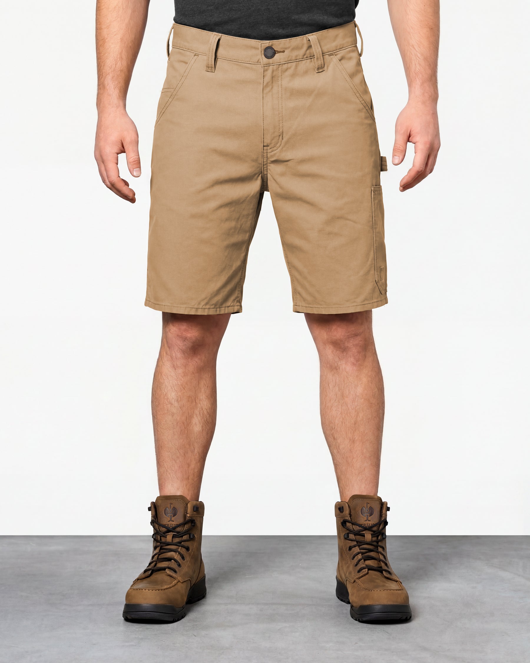 Model wearing Engelbert Strauss e.s. iconic shorts in almond brown, showing the fit, length, waistband, and front pocket layout of the classic work shorts with functional pocket details.