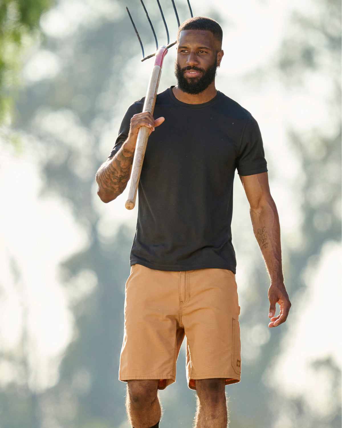Engelbert Strauss e.s. iconic shorts in almond brown in a lifestyle action view, highlighting the practical pocket access and durable workwear silhouette.
