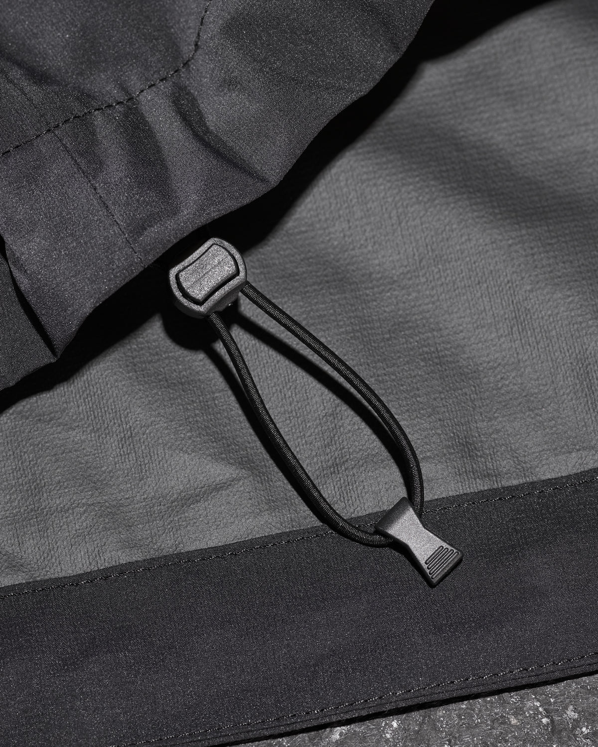 Close-up of packable windbreaker fabric and zipper details on STRAUSS e.s.trail light pack windbreaker in black