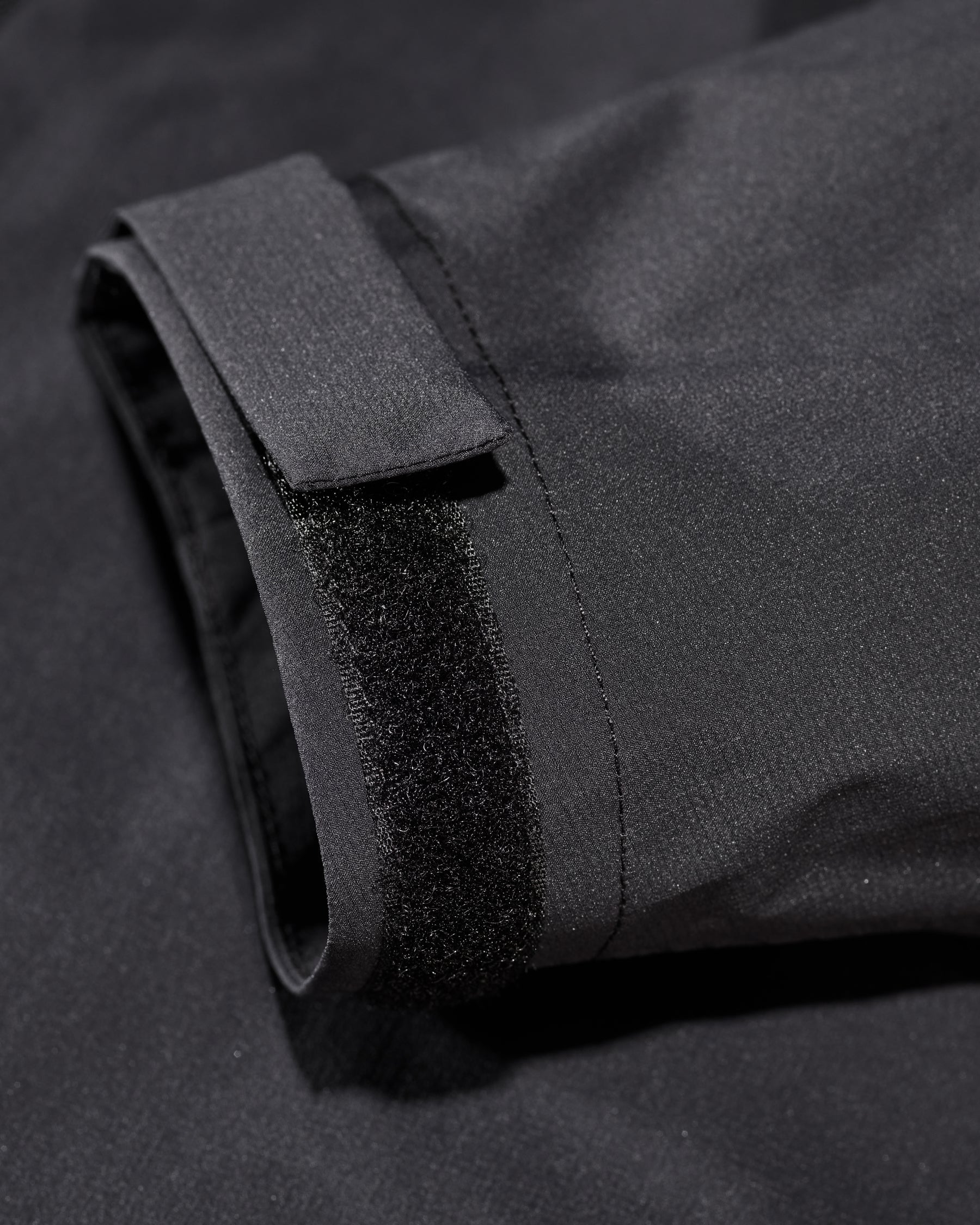 Close-up of hood and pocket details on STRAUSS e.s.trail light pack windbreaker in black