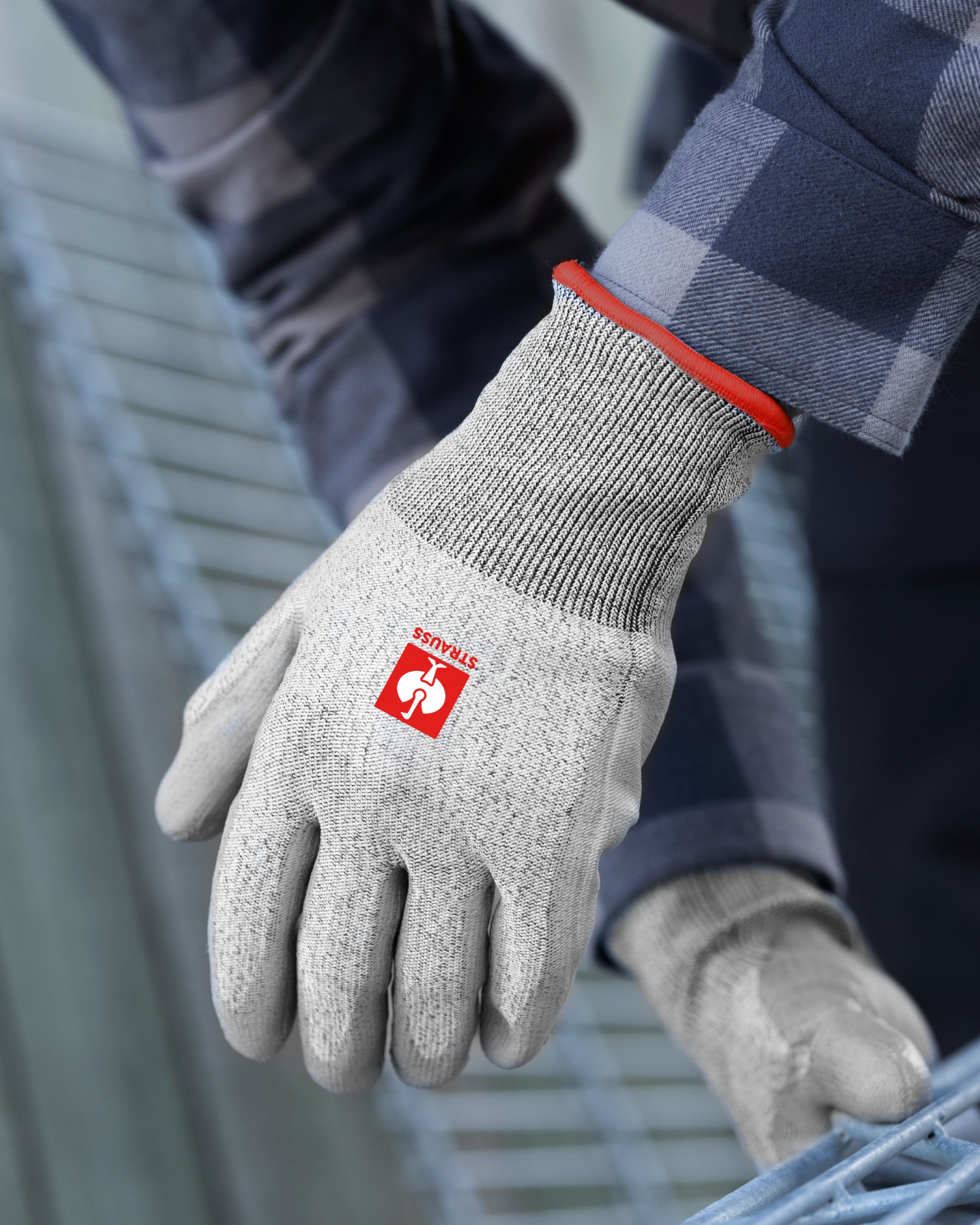 A worker wears gray melange STRAUSS A3 PU cut protection gloves while gripping a hand tool at a workbench.