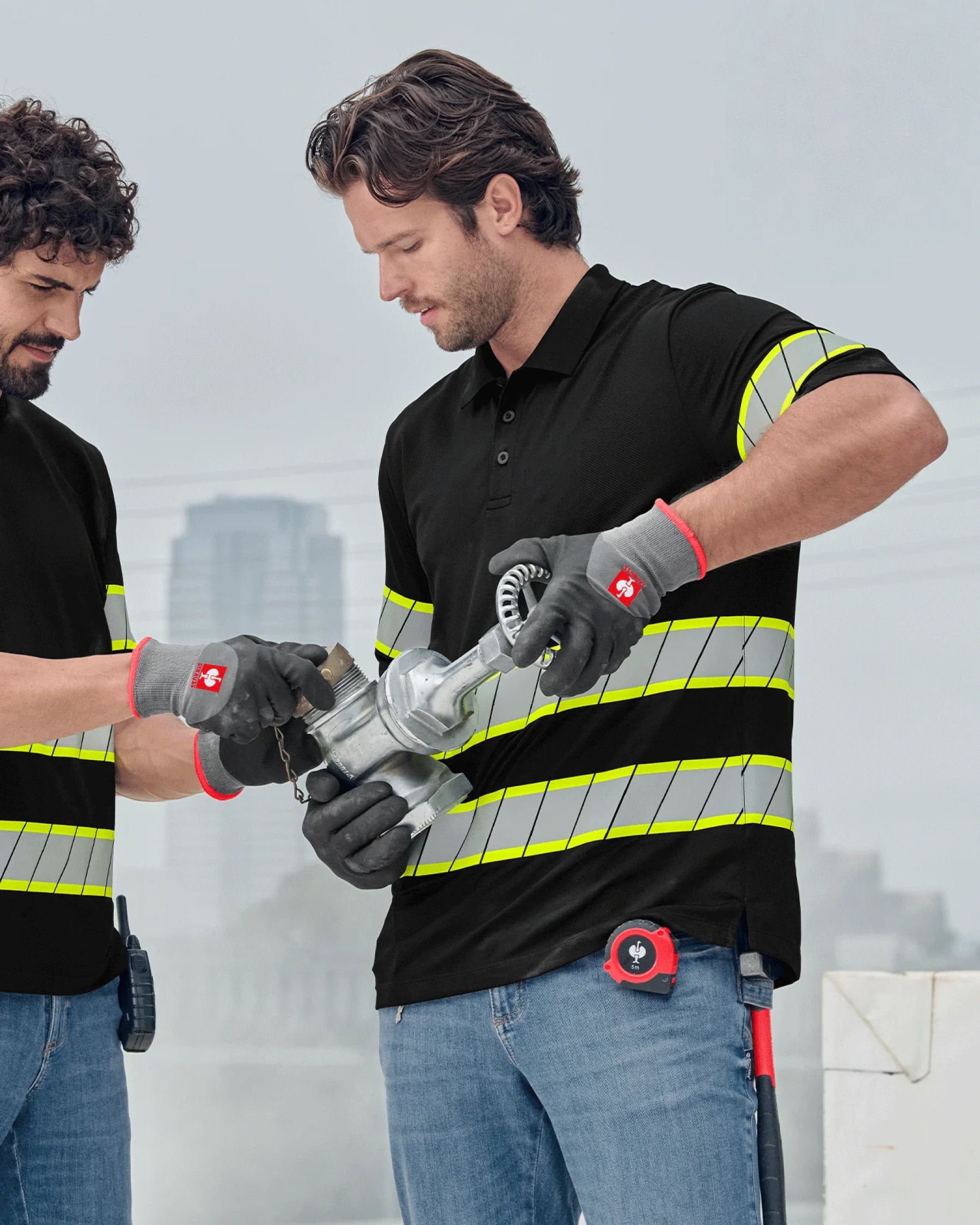 A worker in STRAUSS workwear uses black and gray evertouch winter nitrile foam gloves while handling jobsite materials.