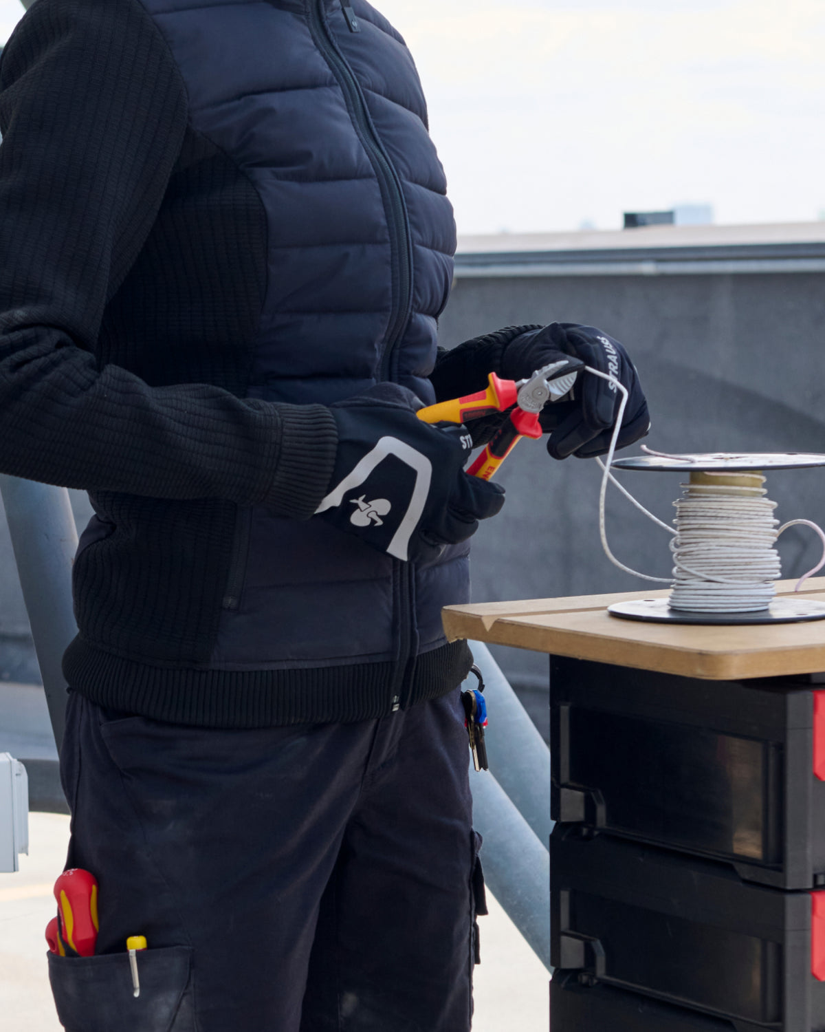 A close work scene shows black and basalt gray STRAUSS e.s.trail winter gloves protecting hands during a task.