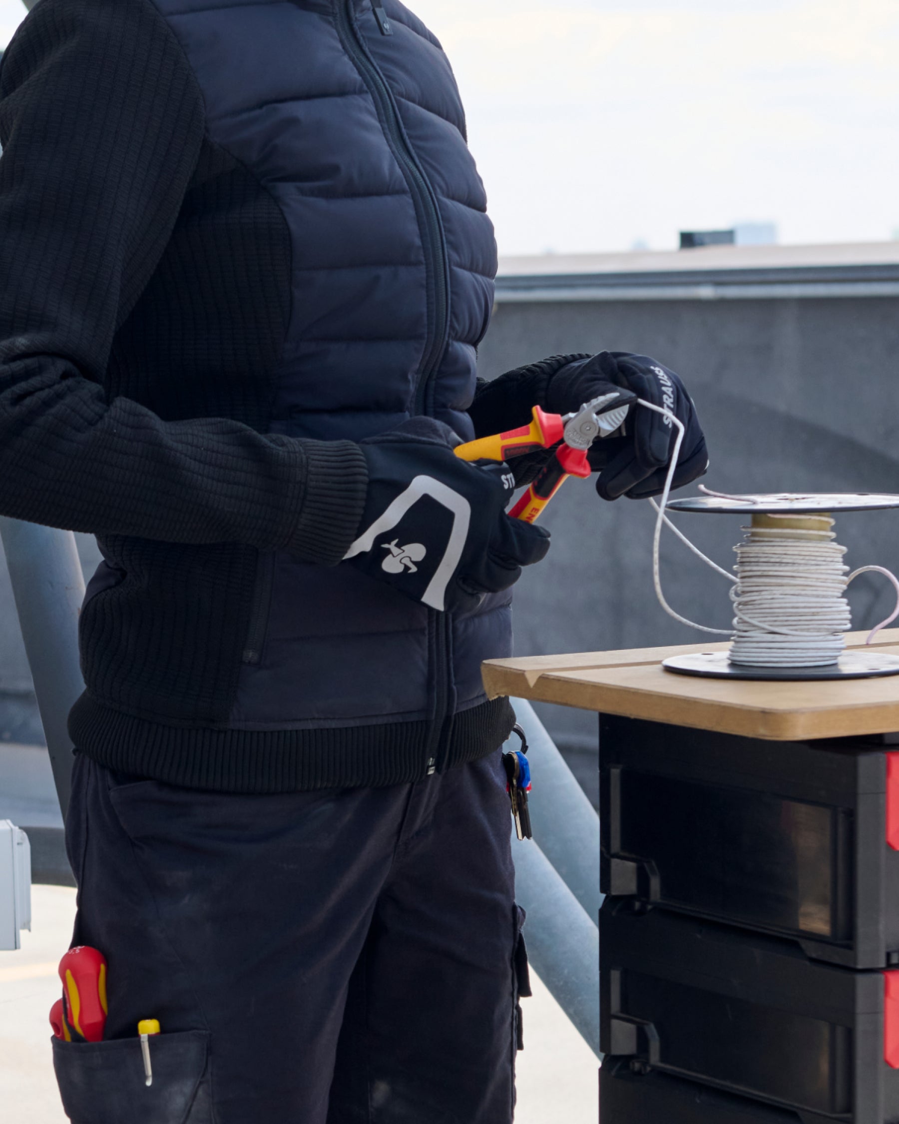 A close work scene shows black and basalt gray STRAUSS e.s.trail winter gloves protecting hands during a task.