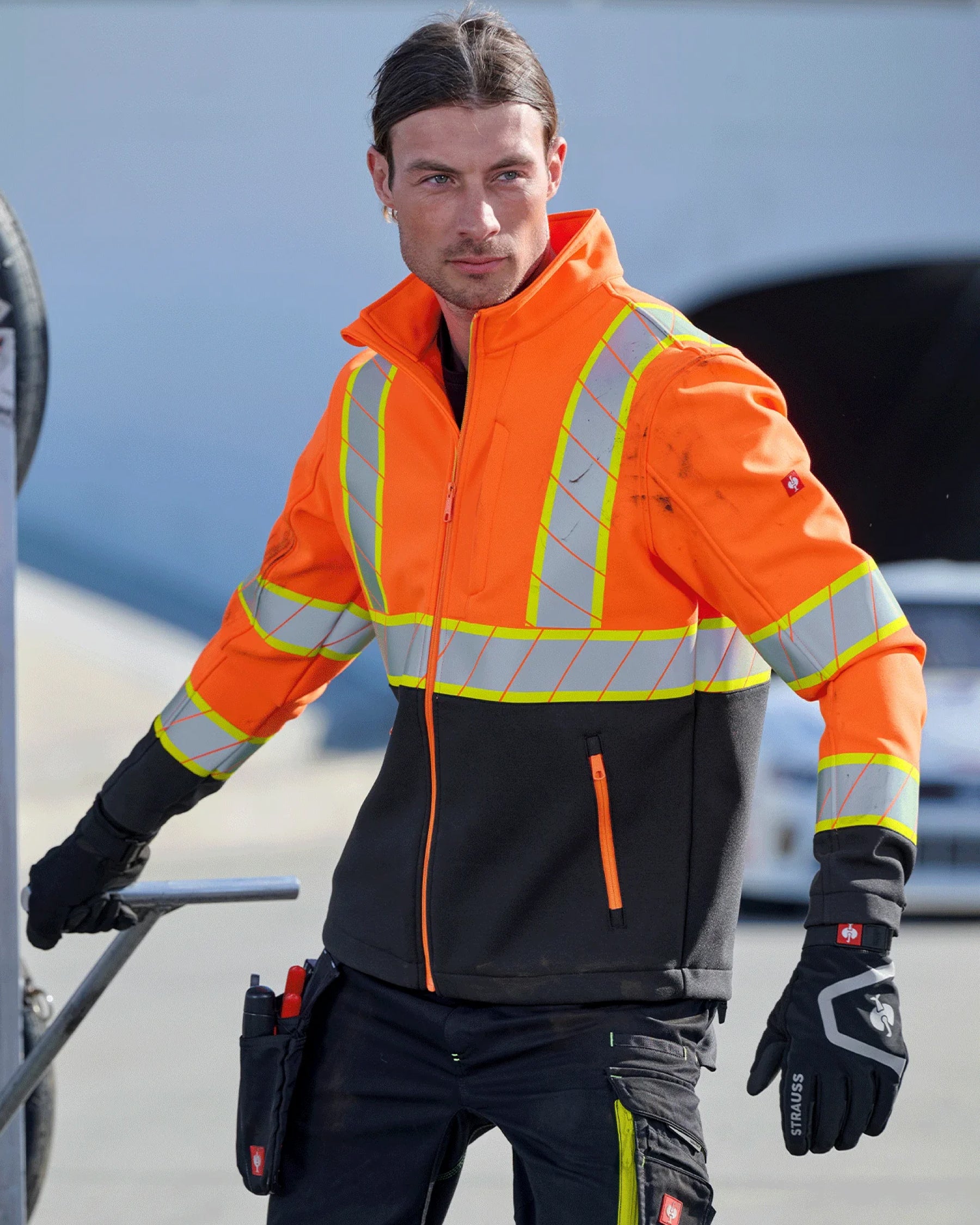 A worker in STRAUSS workwear uses black and basalt gray e.s.trail winter gloves while handling jobsite materials.