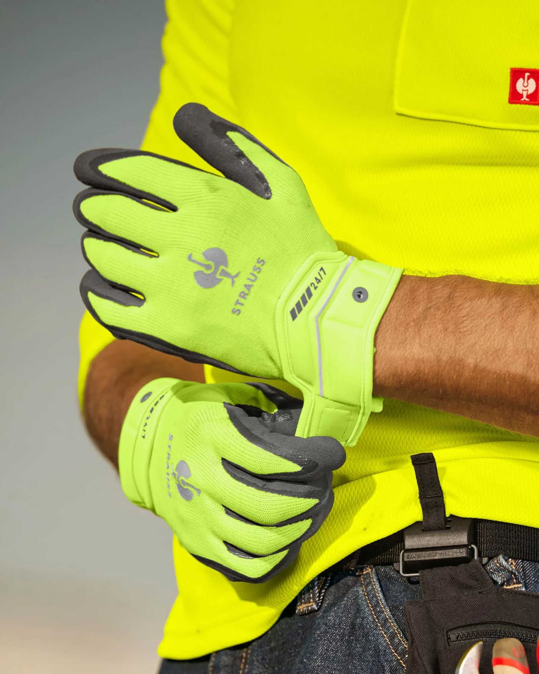 A worker wears neon yellow and anthracite STRAUSS e.s.motion 24/7 hybrid gloves.