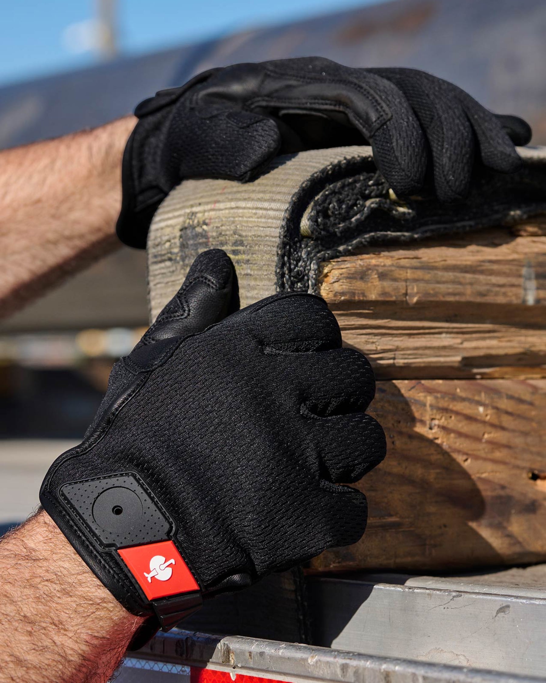 A worker wears black STRAUSS light assembly protection gloves during a task.