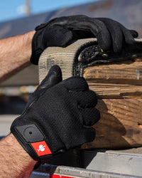 A worker wears black STRAUSS light assembly protection gloves during a task.