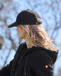 A model wears a black STRAUSS e.s.e:pic cap with a casual STRAUSS workwear outfit.