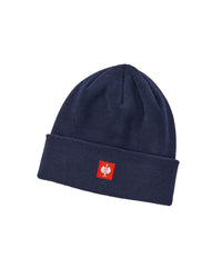 A navy blue knit beanie hat with a folded cuff, featuring a small red square patch on the front with a white stylized logo.