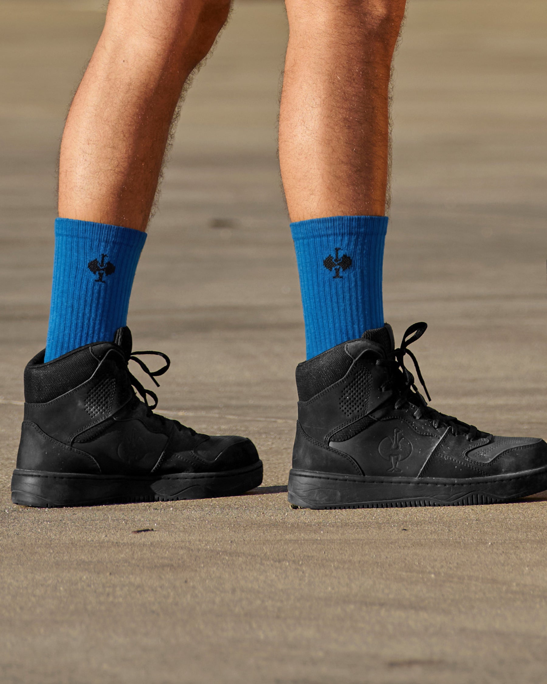A person wears gentian blue and graphite STRAUSS classic all-round high-cut socks, 3-pack with work shoes in a casual product scene.
