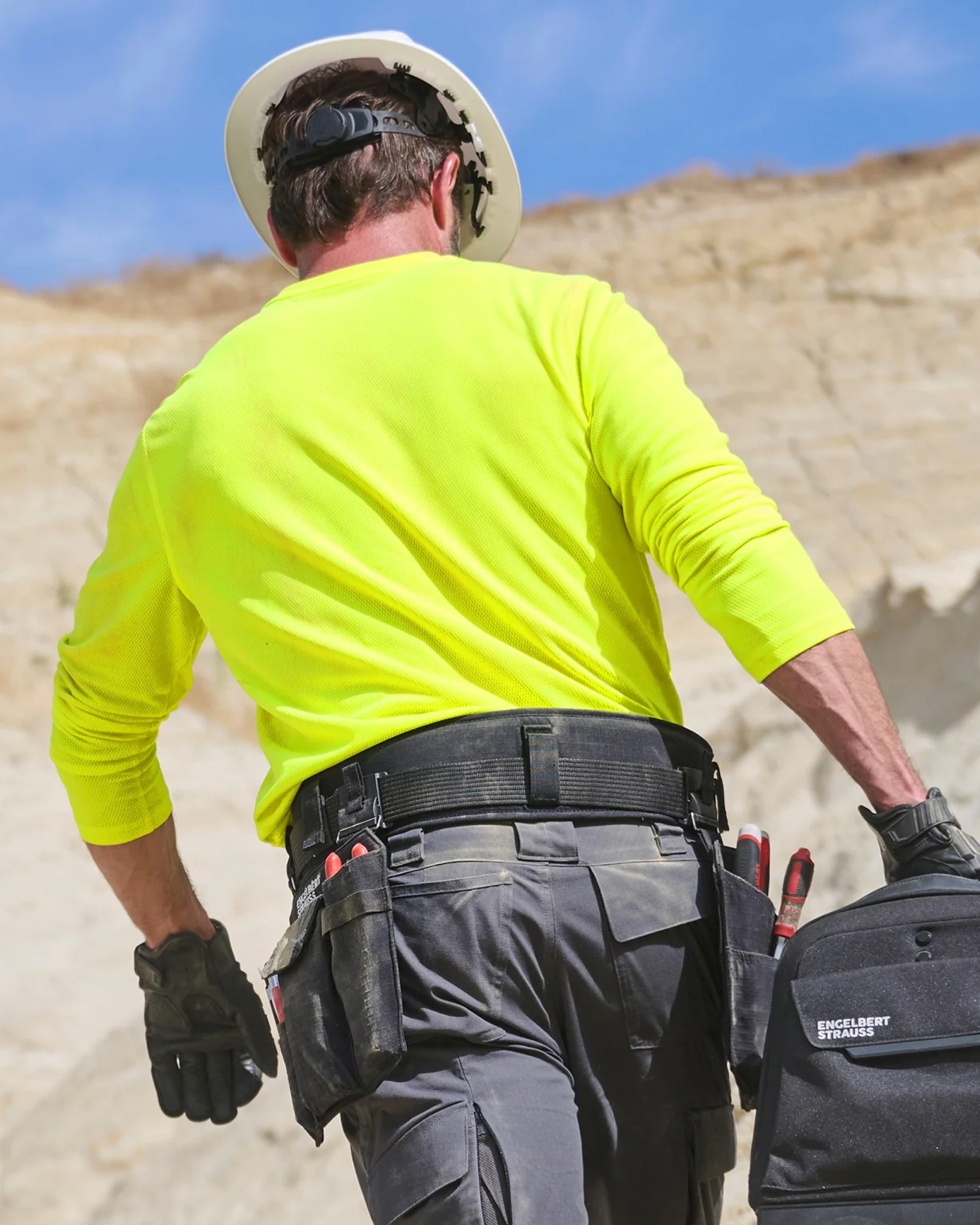 A worker in STRAUSS work pants uses a black e.s.iconic tool belt with attached tool storage.