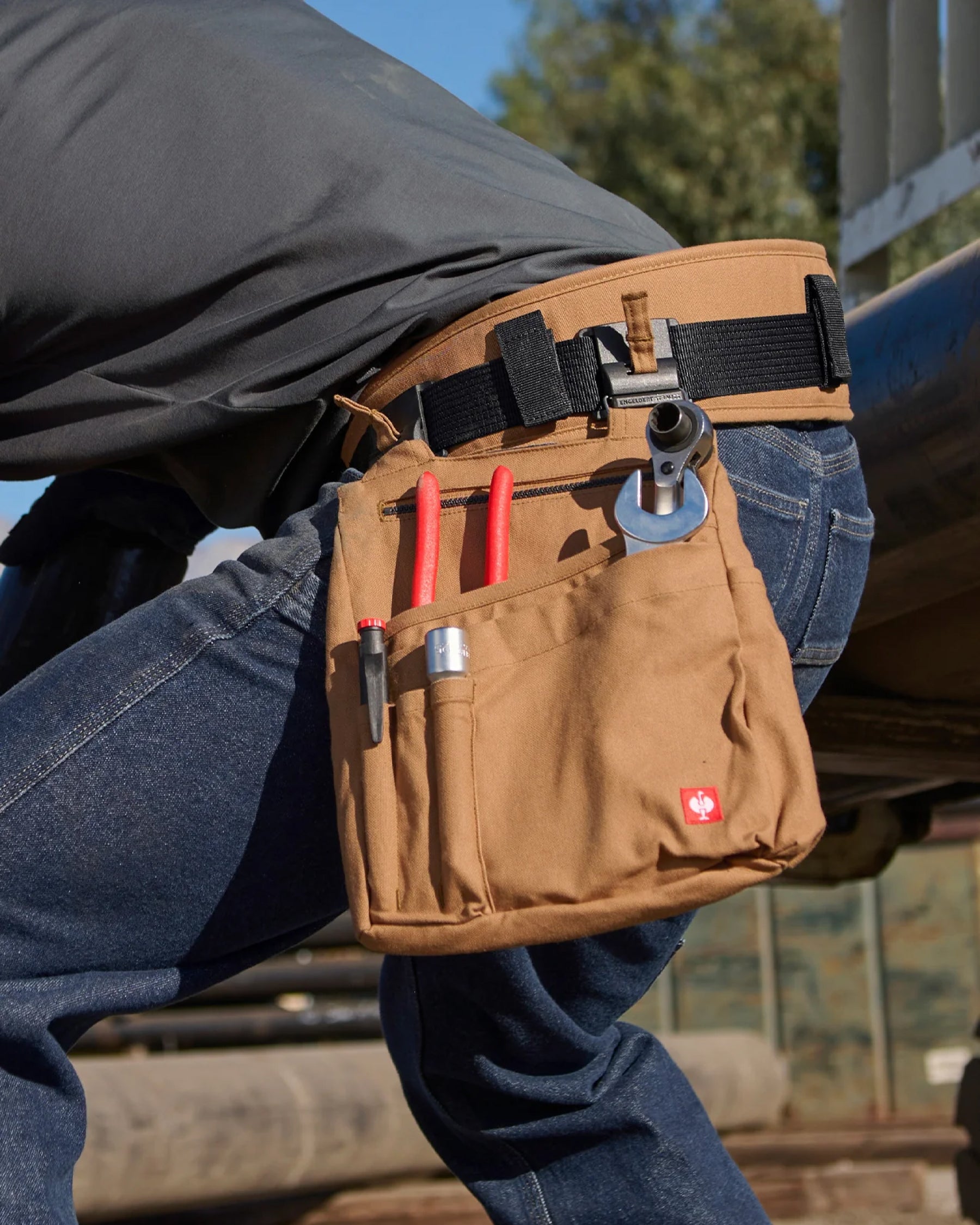 A worker wears a almond brown STRAUSS e.s.iconic tool belt with work pants and modular tool accessories.