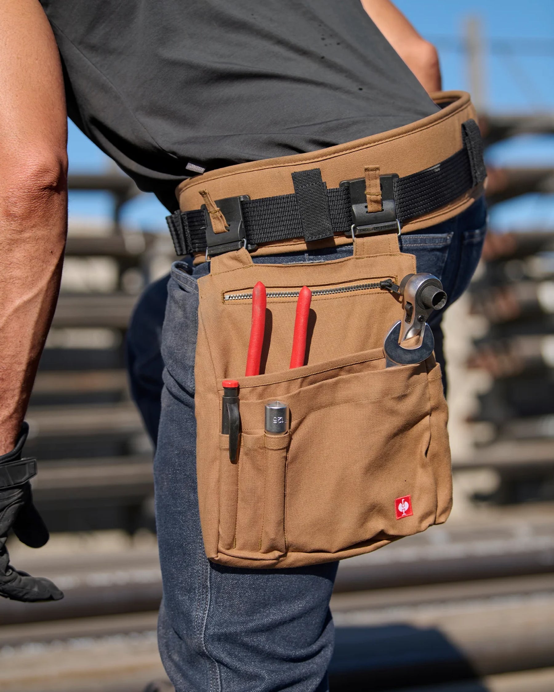 A close workwear scene shows a almond brown STRAUSS e.s.iconic tool belt securing utility pants.