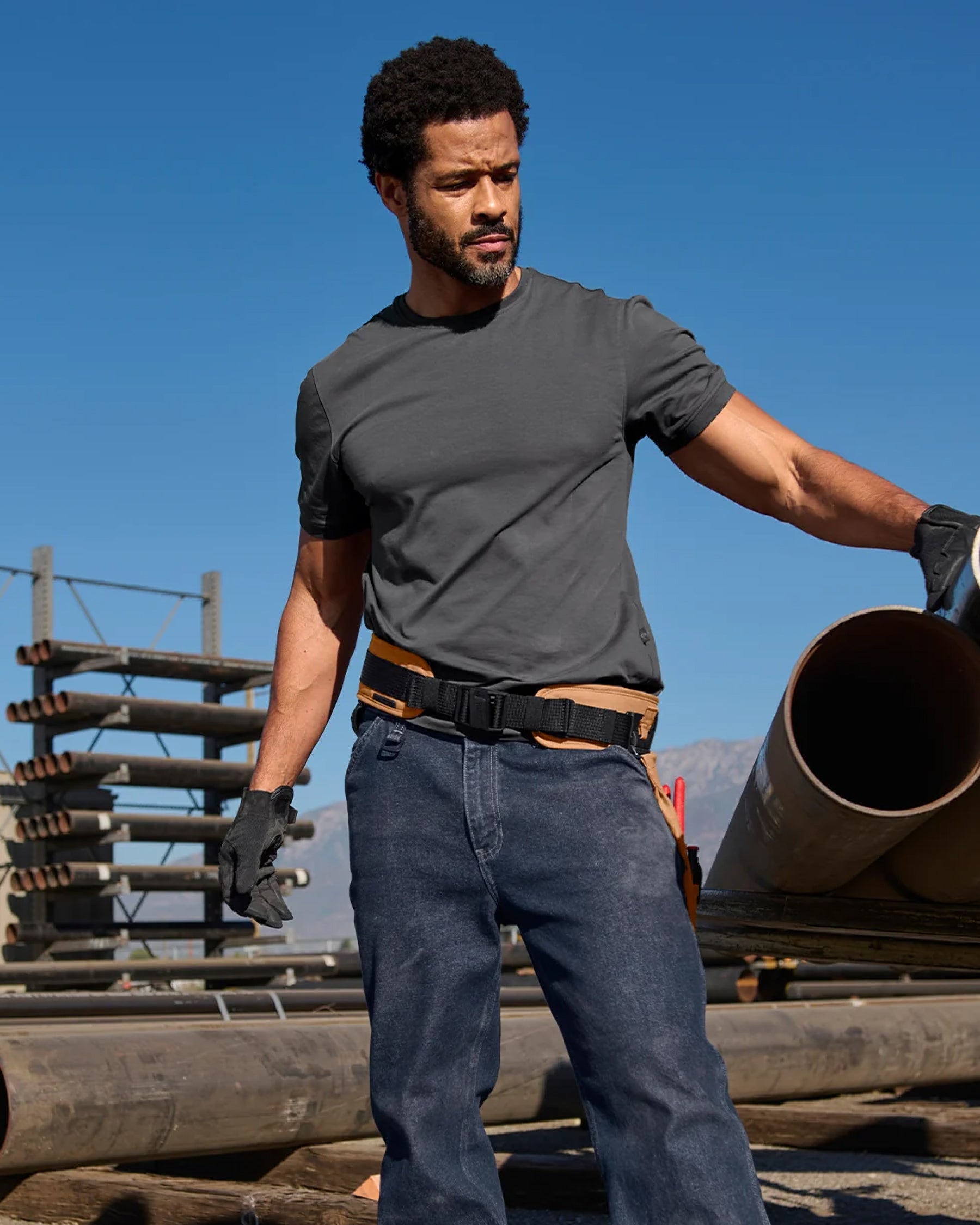 A worker in STRAUSS work pants uses a almond brown e.s.iconic tool belt with attached tool storage.