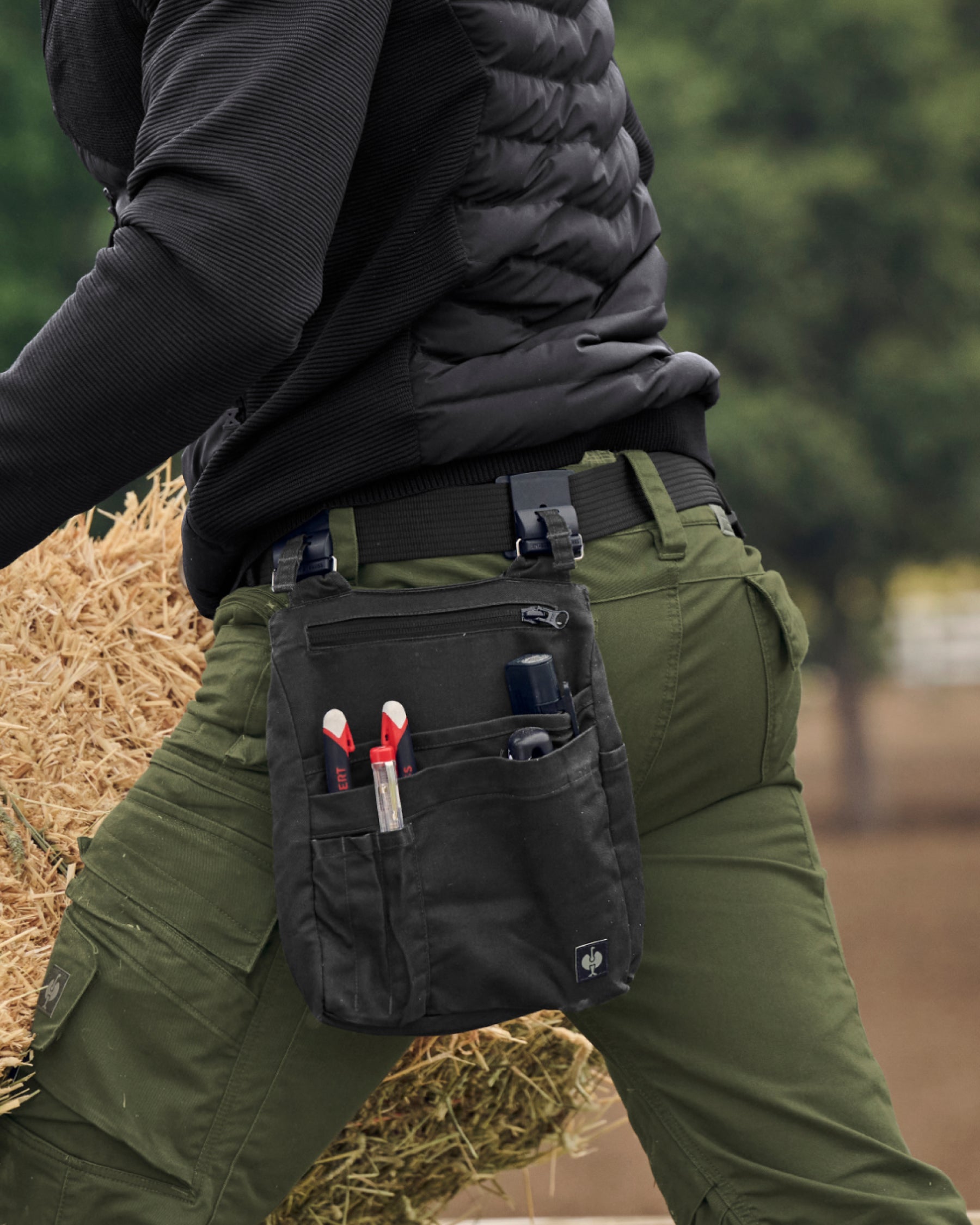 A close workwear scene shows a black STRAUSS e.s.tool concept belt securing utility pants.