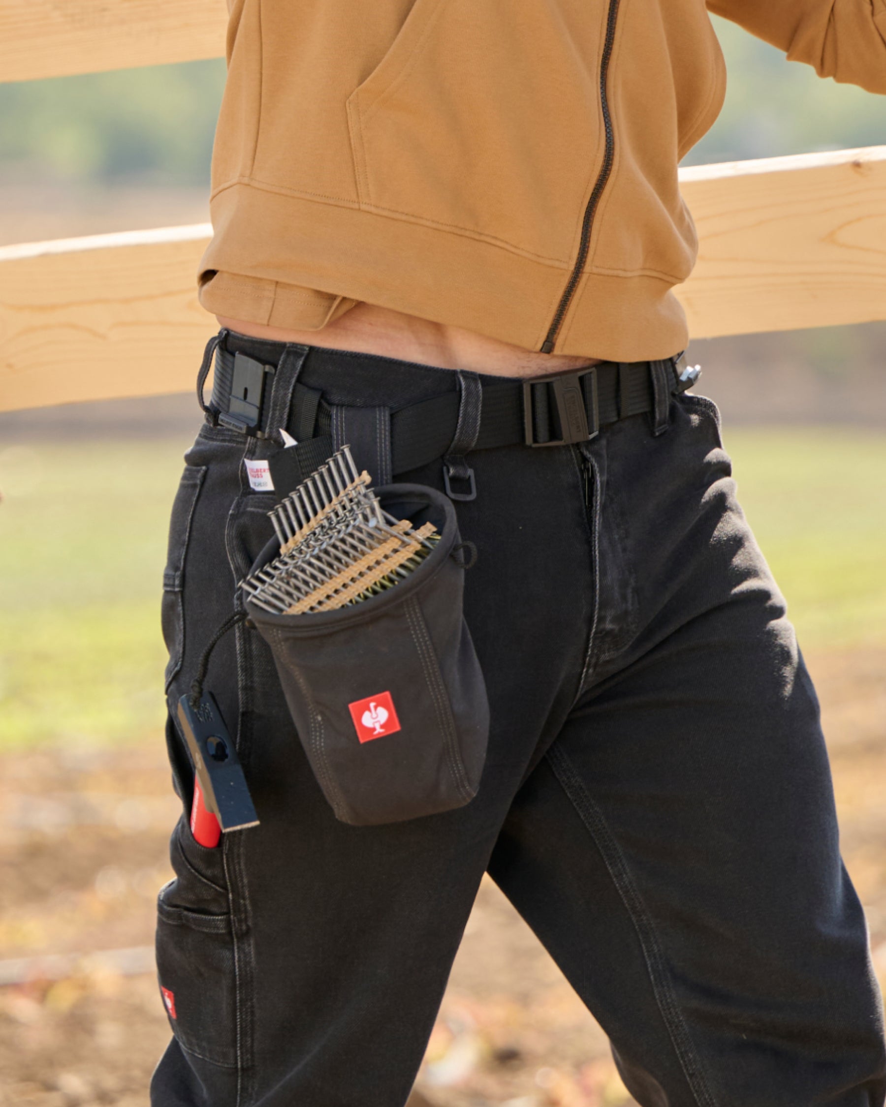 A worker in STRAUSS work pants uses a black e.s.tool concept belt with attached tool storage.