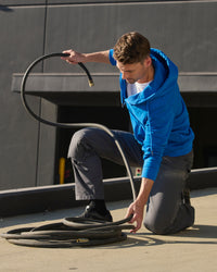A worker kneels in STRAUSS work pants with graphite comfort cell knee pads cushioning the knees.