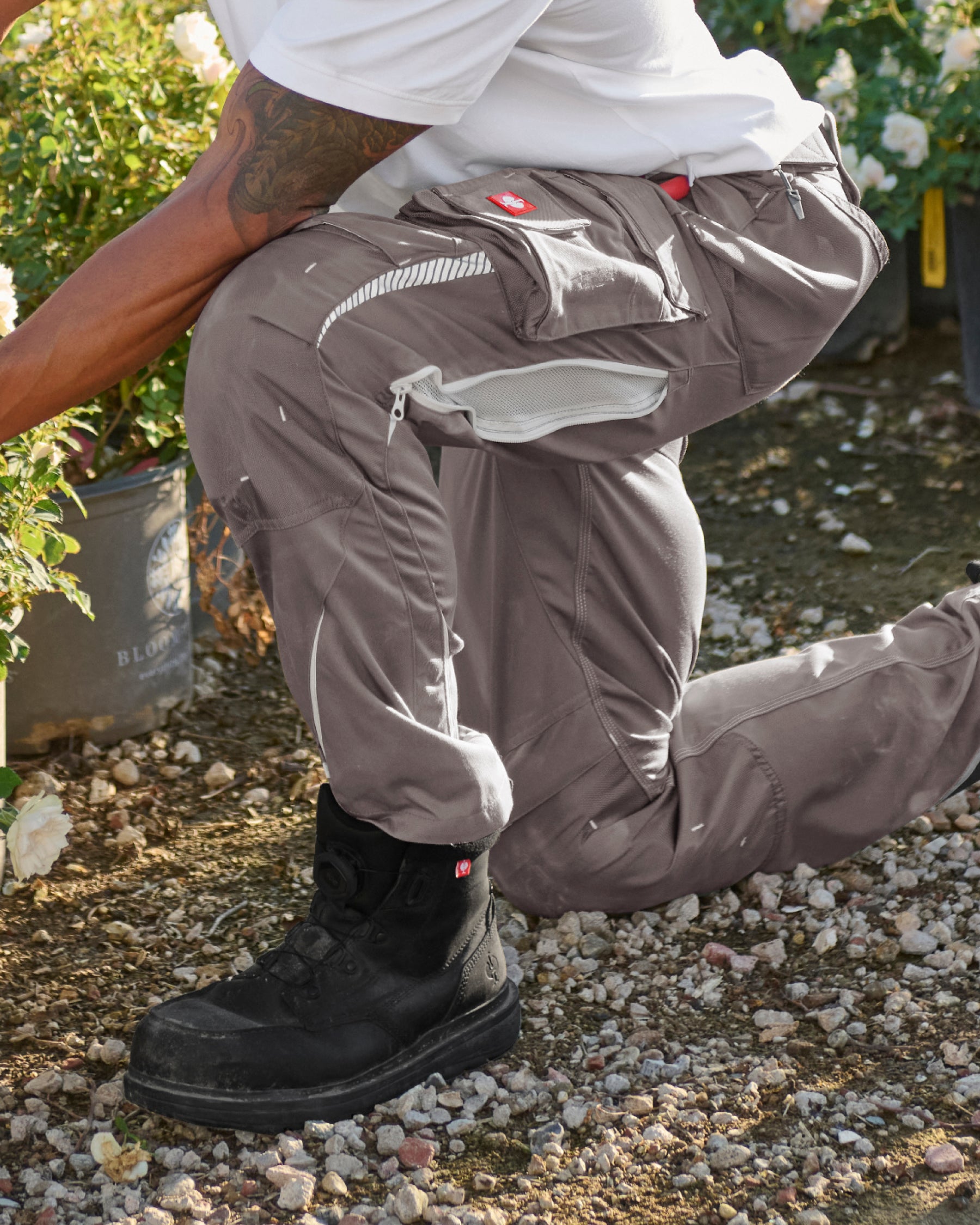 Black STRAUSS flex knee pads are shown inserted in work pants during a kneeling task.