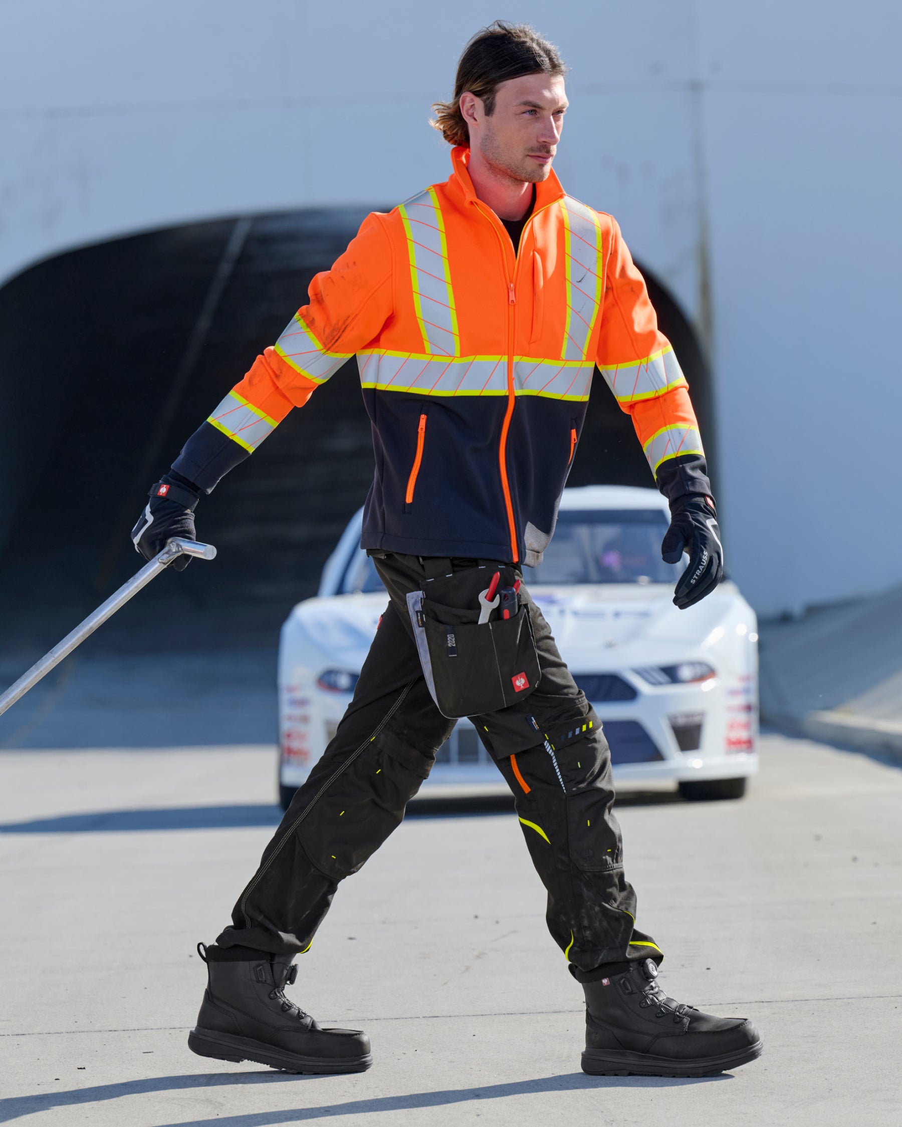 STRAUSS Class 2 high visibility softshell jacket in neon orange and black in use with workwear