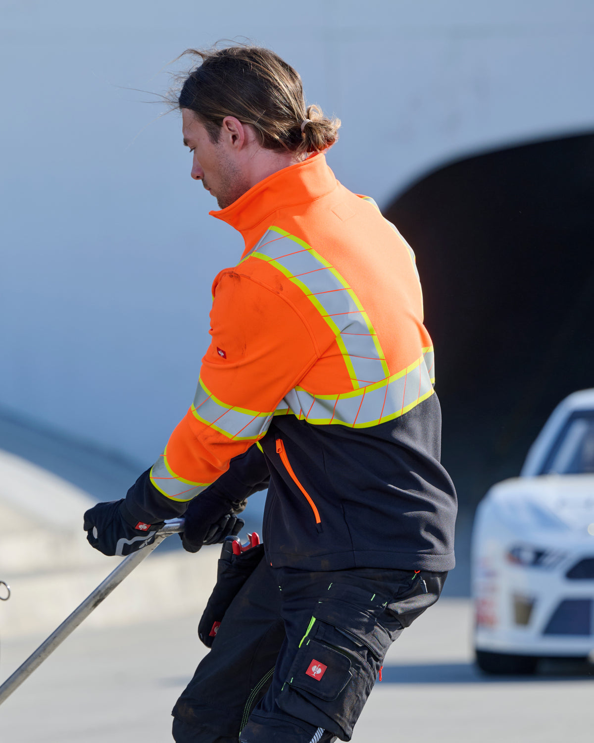 STRAUSS Class 2 high visibility softshell jacket in neon orange and black paired with work pants