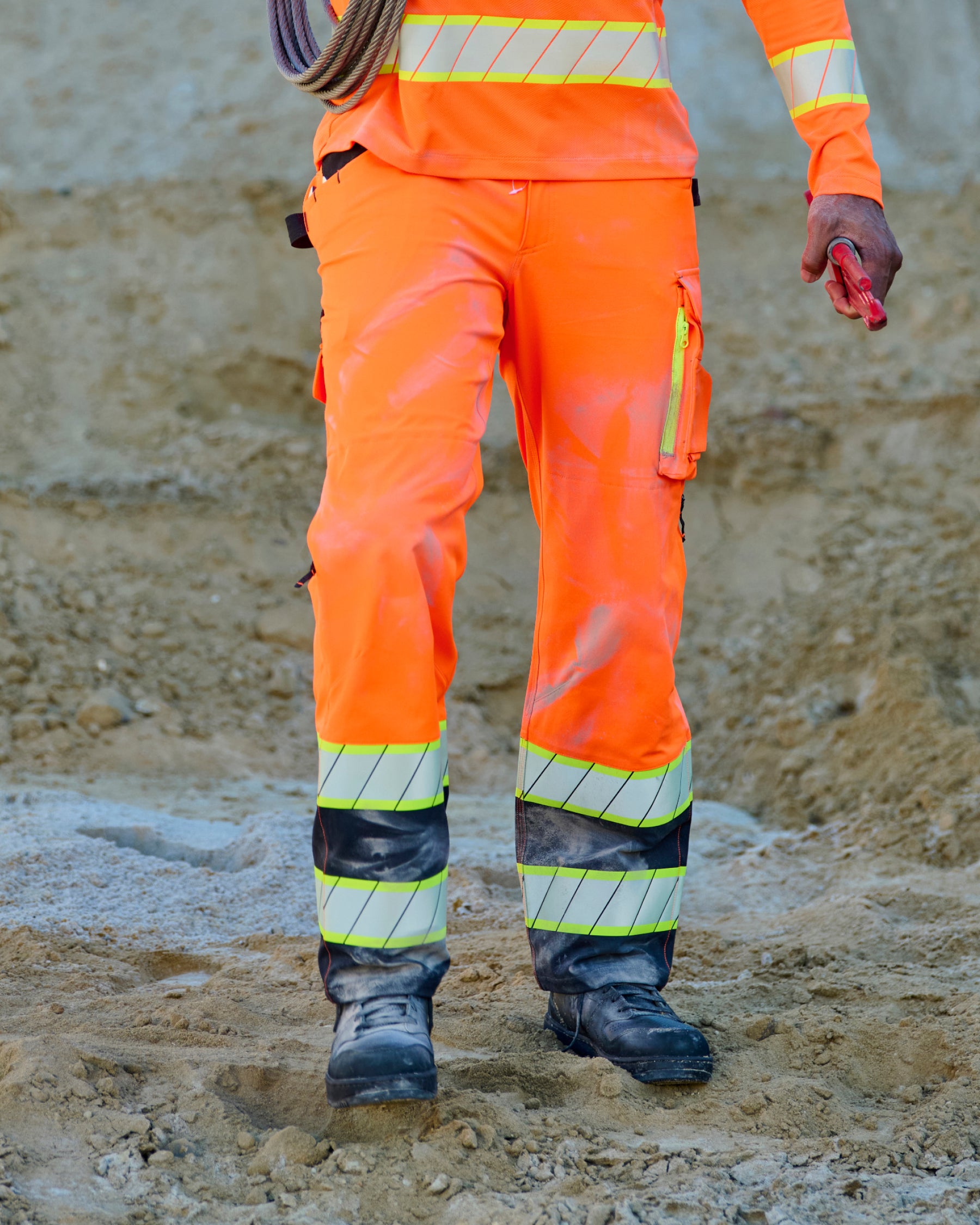 High Visibility Work Pants in neon orange/black worn in a work setting