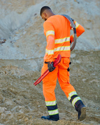 Lifestyle view of High Visibility Work Pants in neon orange/black during work