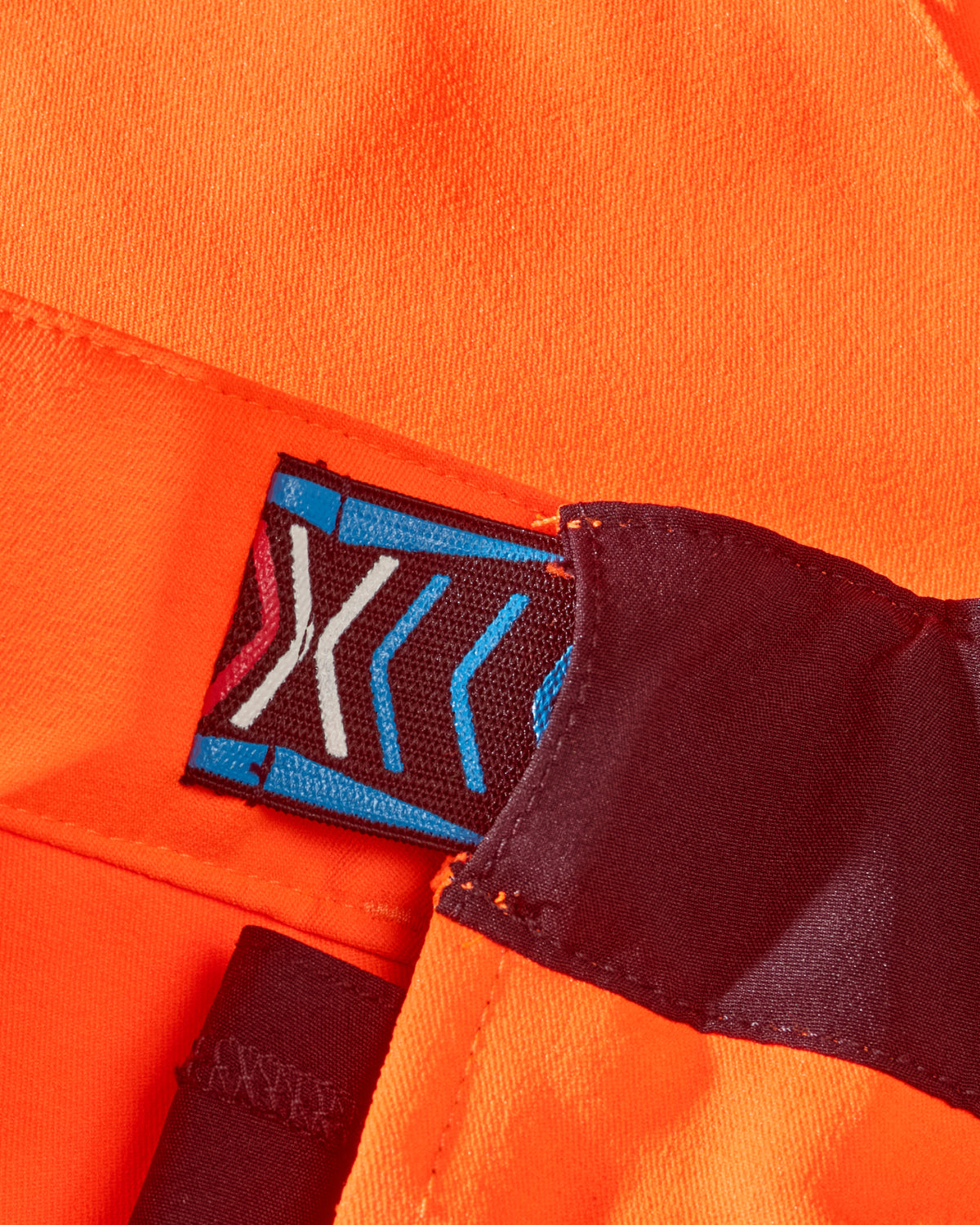 Close-up of reflective workwear details on High Visibility Work Pants in neon orange/black