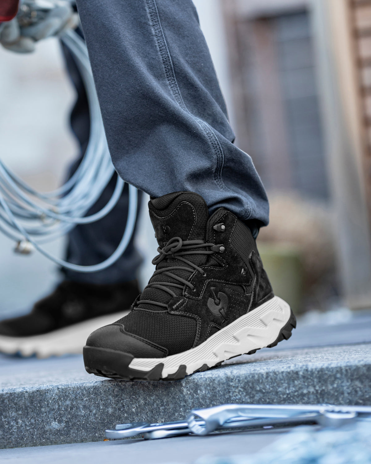 STRAUSS Rimini 6-inch Soft Toe Boot in Black and Crystal gray shown on rough jobsite ground