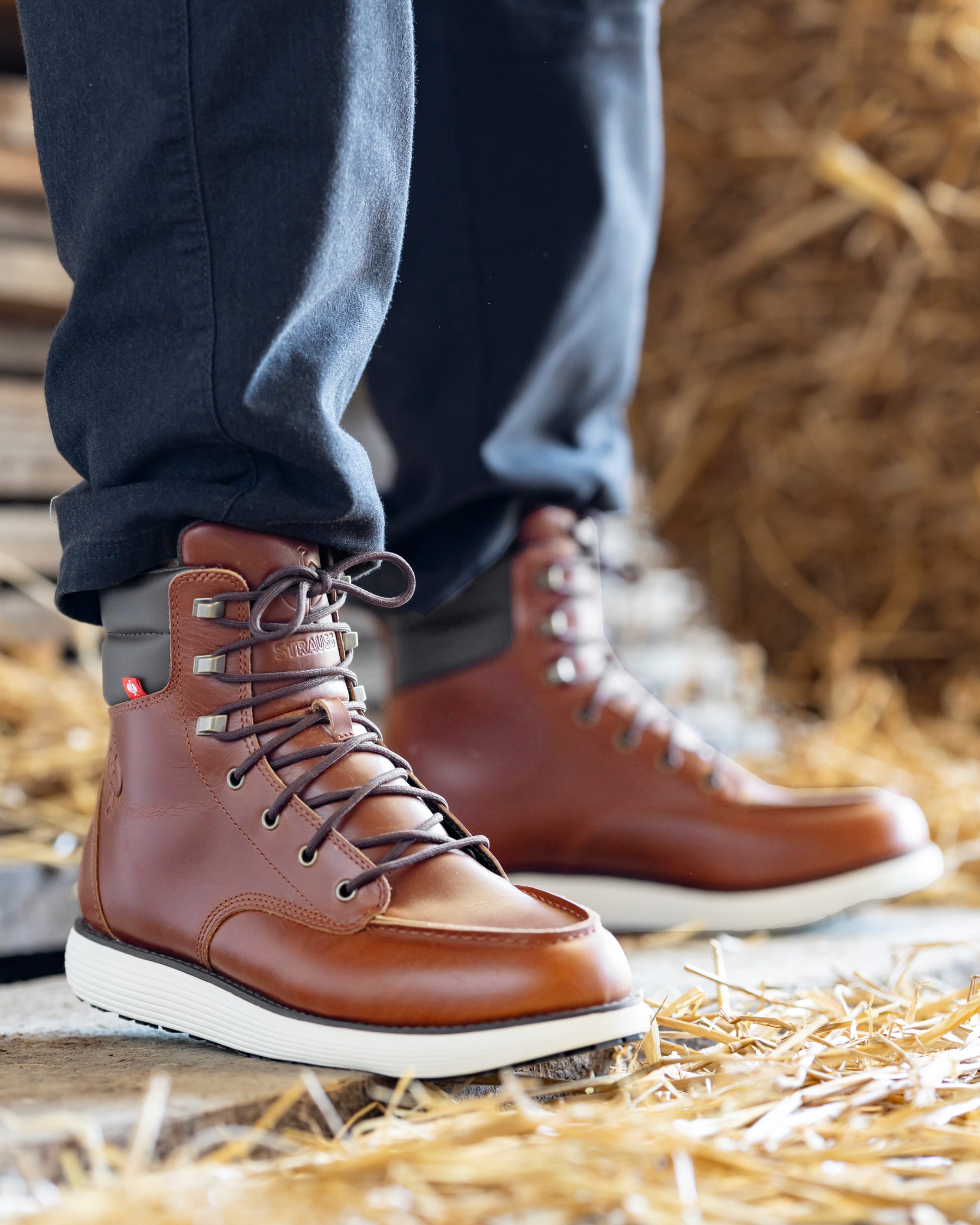 STRAUSS Boulder 6-inch Soft Toe Boot in Red brown shown on rough jobsite ground