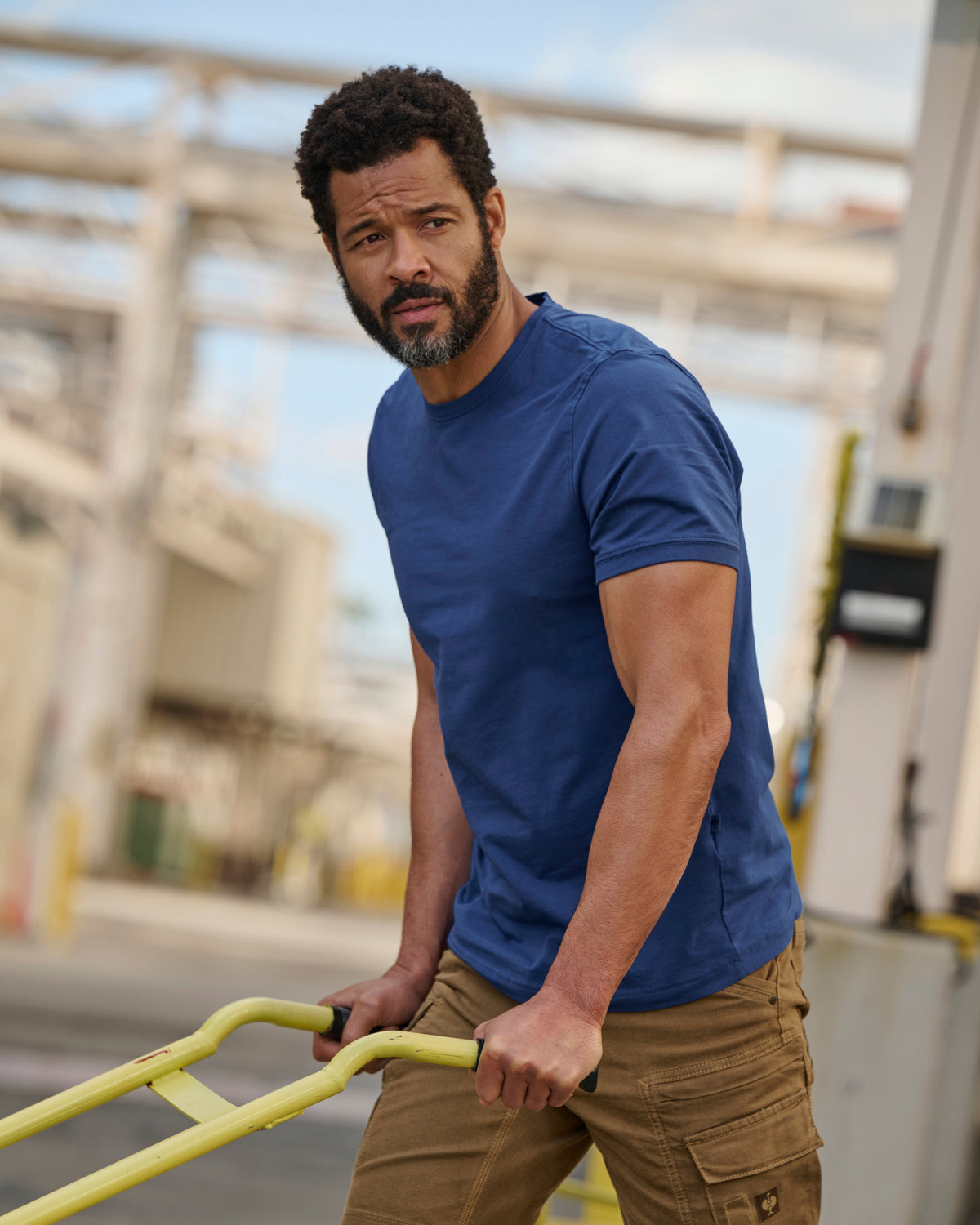 A worker wears the STRAUSS Cotton Stretch T-Shirt in alkali blue with tan work pants while working