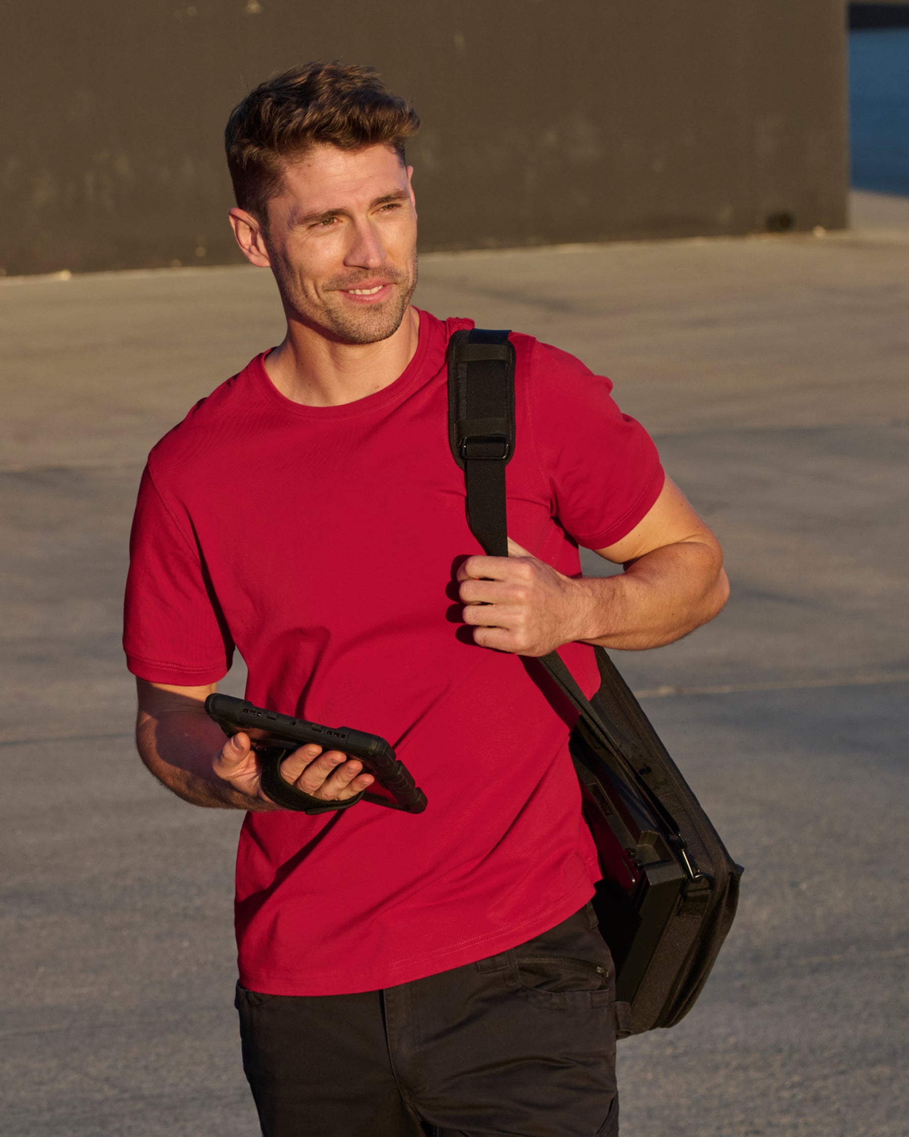 A worker wears the STRAUSS Cotton Stretch T-Shirt in fire red with black work pants
