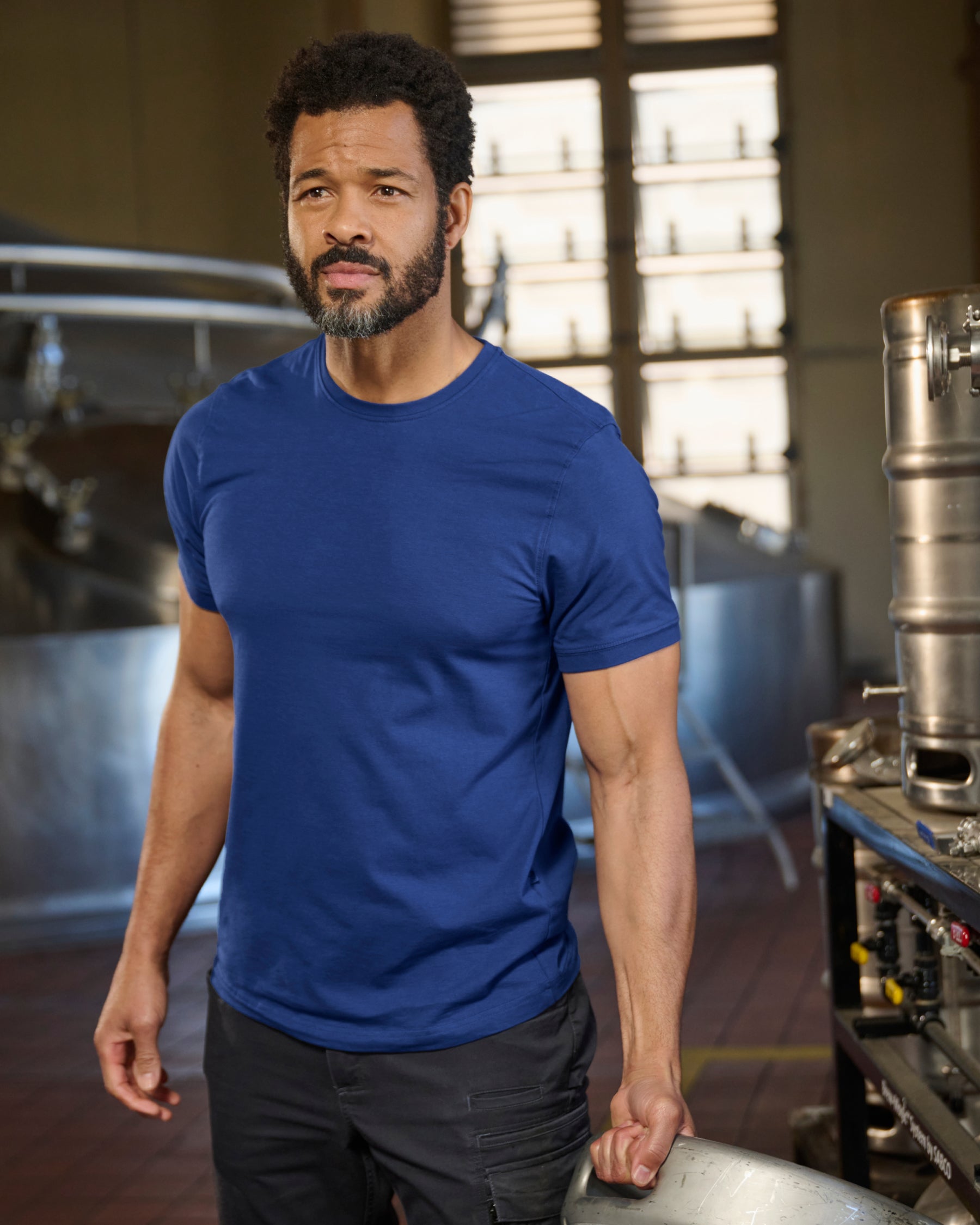 A worker wears the STRAUSS Cotton Stretch T-Shirt in royal blue with tan work pants on a sunny jobsite