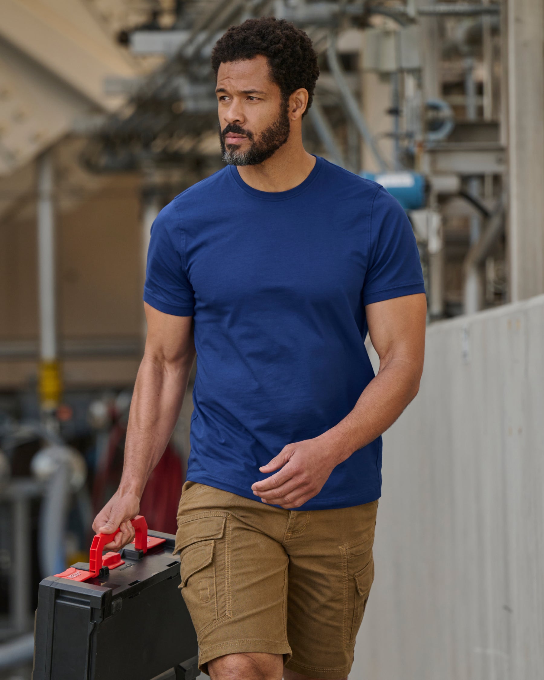 A worker wears the STRAUSS Cotton Stretch T-Shirt in royal blue with tan work pants while working
