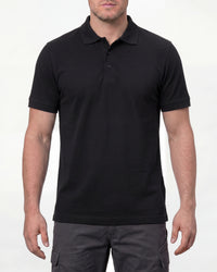 A model wears the STRAUSS Cotton Stretch Polo Shirt in black with tan work pants and work boots in a studio product scene