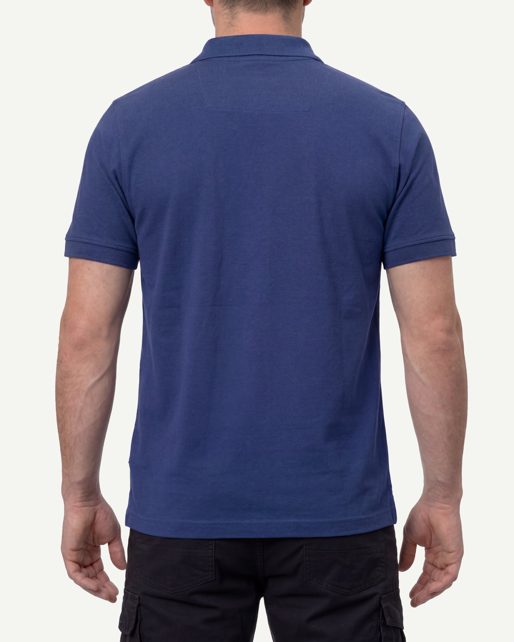 A model wears the STRAUSS Cotton Stretch Polo Shirt in royal blue with tan work pants and work boots, showing the shirt fit