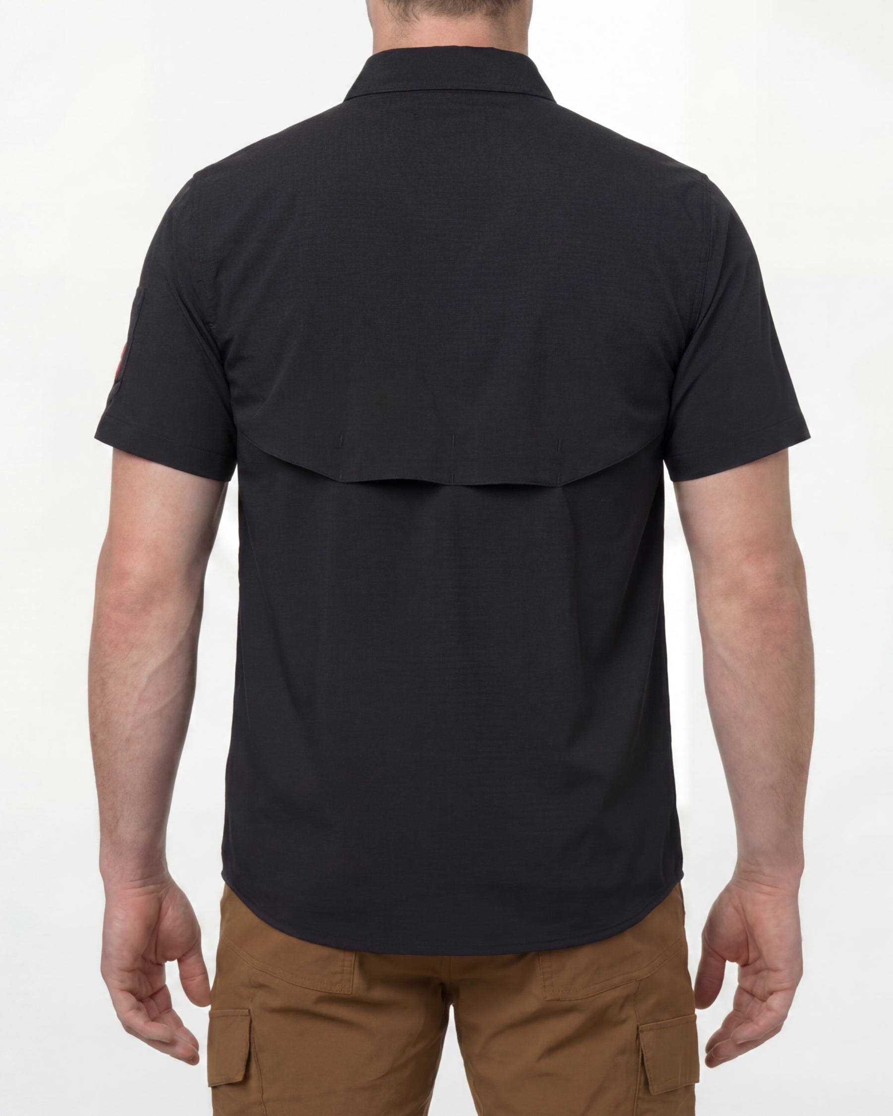 A model wears the STRAUSS e.s.taktik Stretch Ripstop Short Sleeve Work Shirt in black open over a T-shirt with work pants and work boots, showing the shirt fit