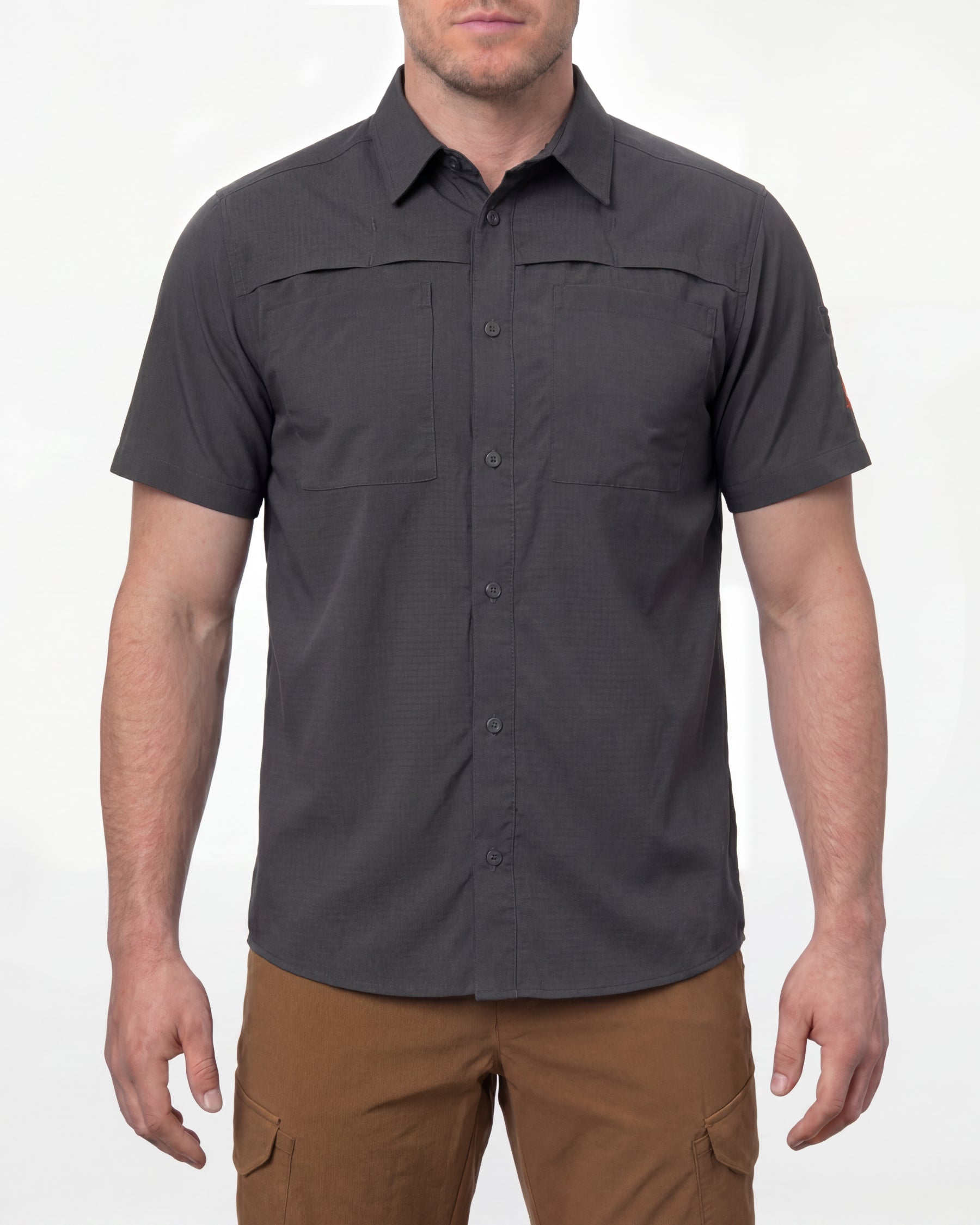 A model wears the STRAUSS e.s.taktik Stretch Ripstop Short Sleeve Work Shirt in carbon gray open over a T-shirt with work pants and work boots in a studio product scene