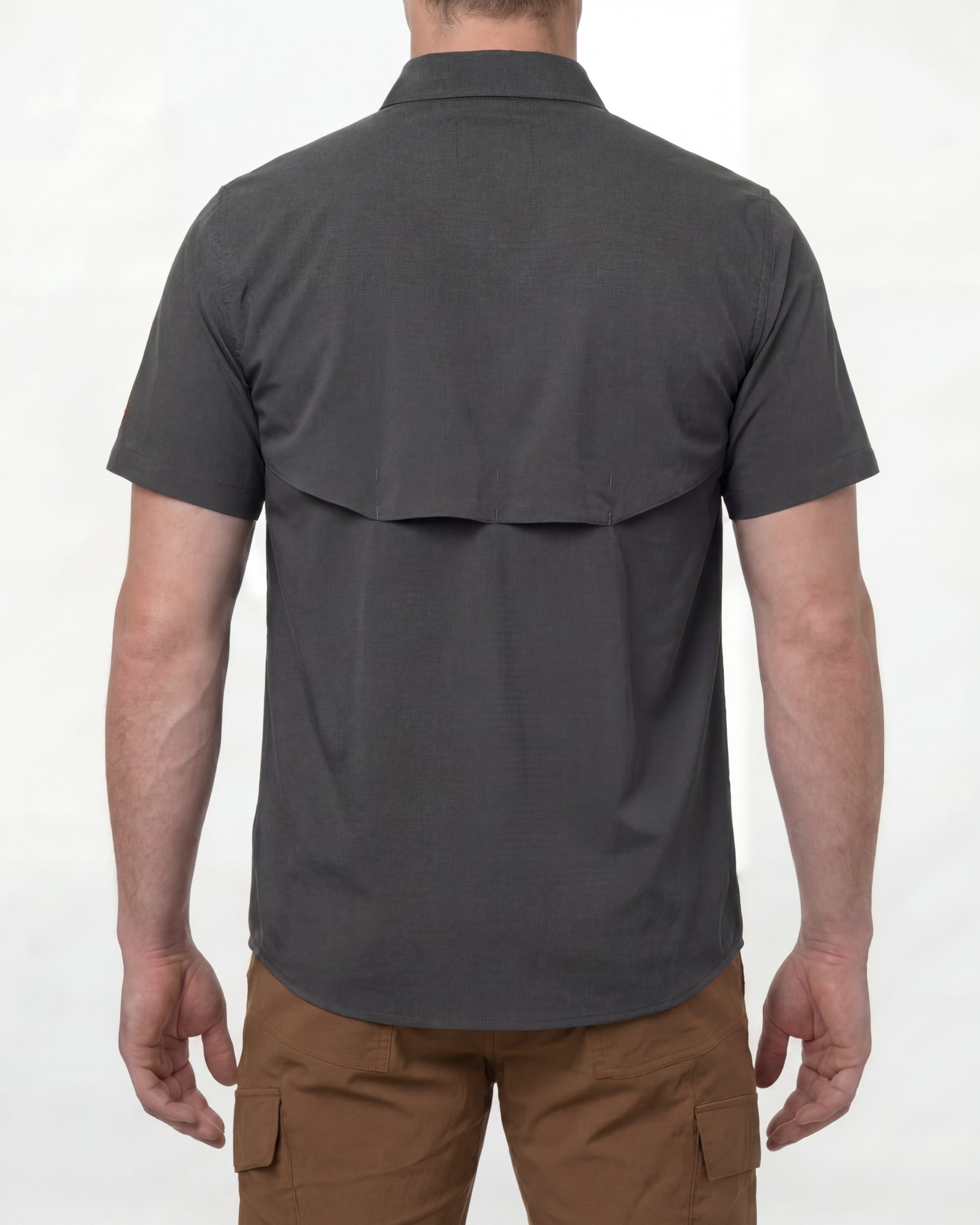 A model wears the STRAUSS e.s.taktik Stretch Ripstop Short Sleeve Work Shirt in carbon gray open over a T-shirt with work pants and work boots, showing the shirt fit