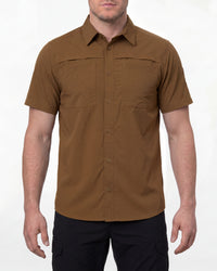 A model wears the STRAUSS e.s.taktik Stretch Ripstop Short Sleeve Work Shirt in desert brown open over a T-shirt with work pants and work boots in a studio product scene