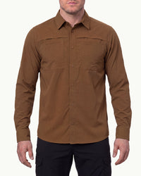 A model wears the STRAUSS e.s.taktik Stretch Ripstop Long Sleeve Work Shirt in desert brown open over a T-shirt with work pants and work boots in a studio product scene