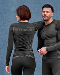 A woman wears the Women's STRAUSS e.s.trail pure Warm Seamless Thermal Long Sleeve Shirt in black and basalt gray