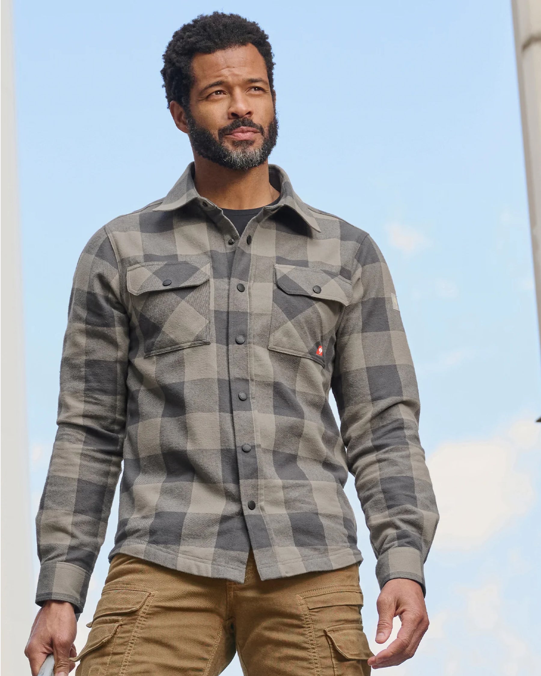 A worker wears the STRAUSS e.s.iconic Flannel Work Shirt in dolphin gray and carbon gray while being on a jobsite