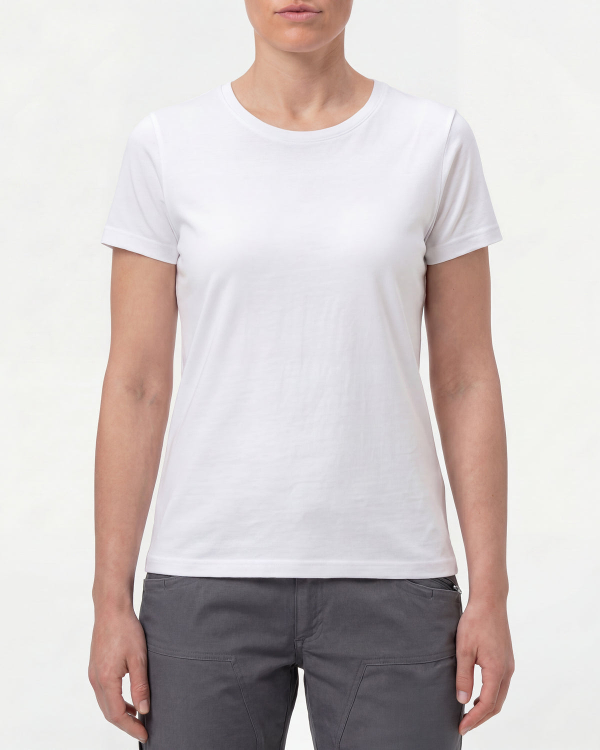 A woman wears the Women's STRAUSS Cotton Stretch T-Shirt in white with work pants and work boots in a studio product scene