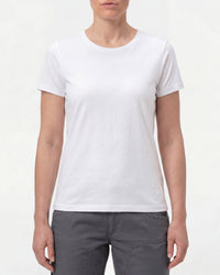 A woman wears the Women's STRAUSS Cotton Stretch T-Shirt in white with work pants and work boots in a studio product scene