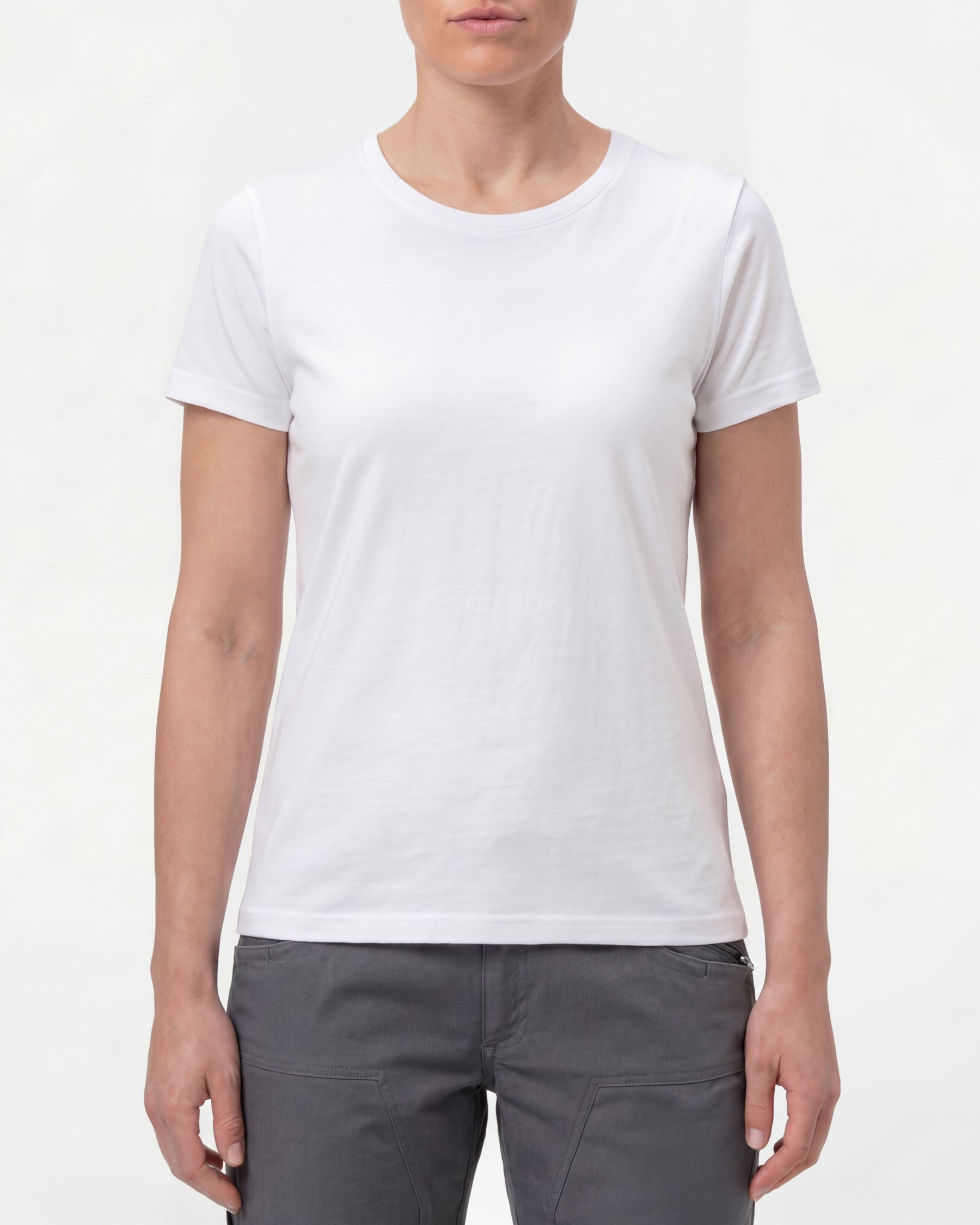A woman wears the Women's STRAUSS Cotton Stretch T-Shirt in white with work pants and work boots in a studio product scene