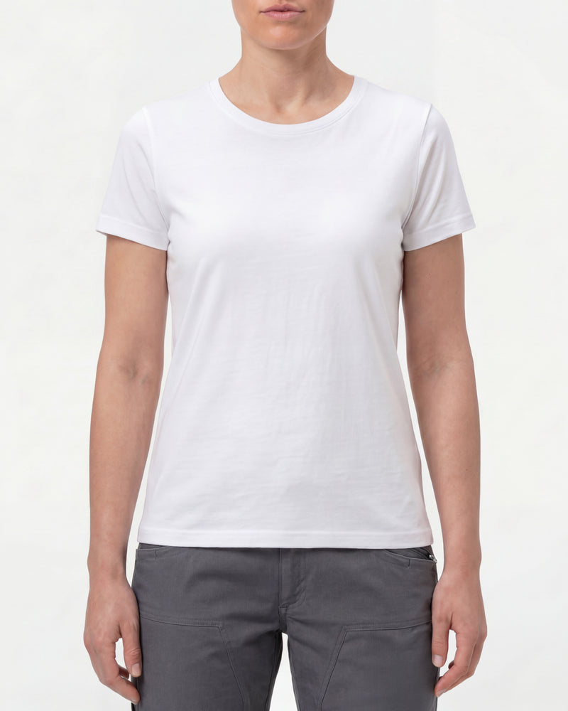 A woman wears the Women's STRAUSS Cotton Stretch T-Shirt in white with work pants and work boots in a studio product scene