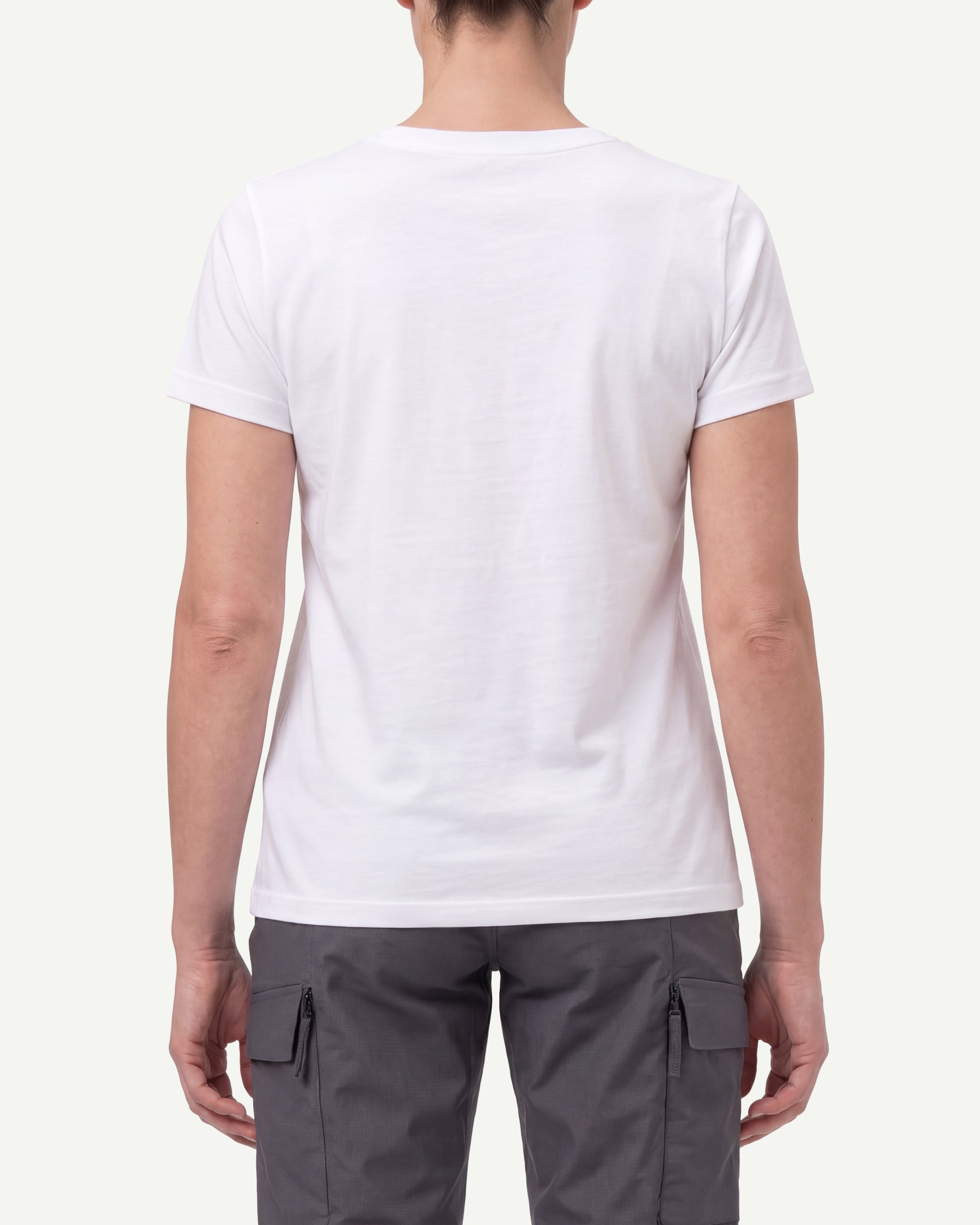 A woman wears the Women's STRAUSS Cotton Stretch T-Shirt in white with work pants and work boots, showing the shirt fit