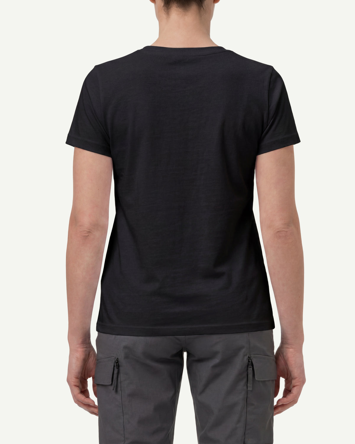 A woman wears the Women's STRAUSS Cotton Stretch T-Shirt in black with work pants and work boots, showing the shirt fit