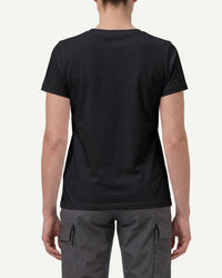 A woman wears the Women's STRAUSS Cotton Stretch T-Shirt in black with work pants and work boots, showing the shirt fit